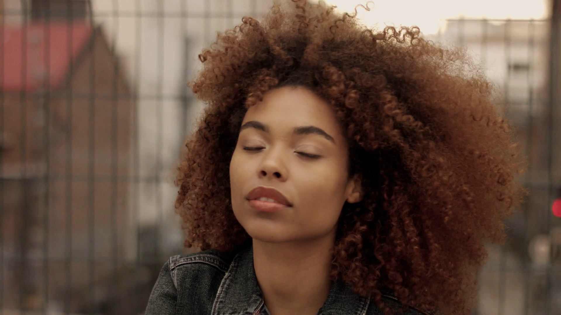 black mixed race woman with big afro curly hair in urban industrial ...